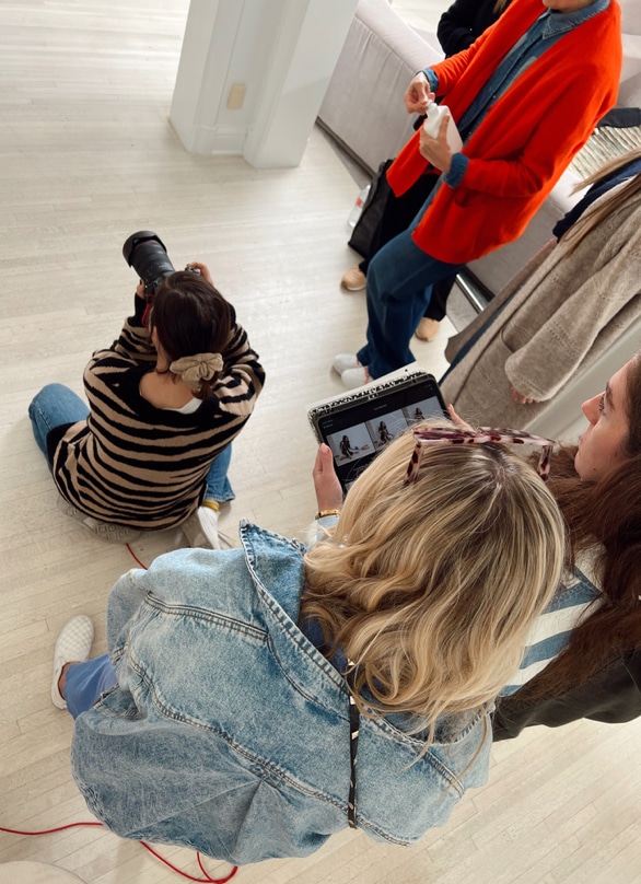 Photographers and designers stand together and collaborate while shooting images for Fall 2023.