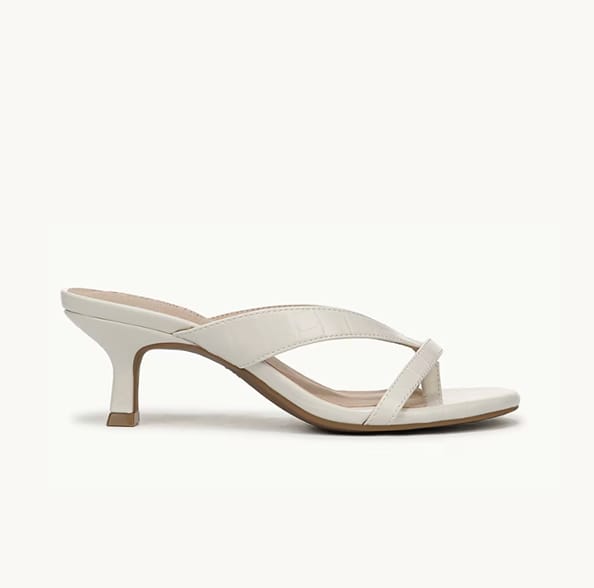 A side view of an off-white heeled sandal with the toe facing right. 