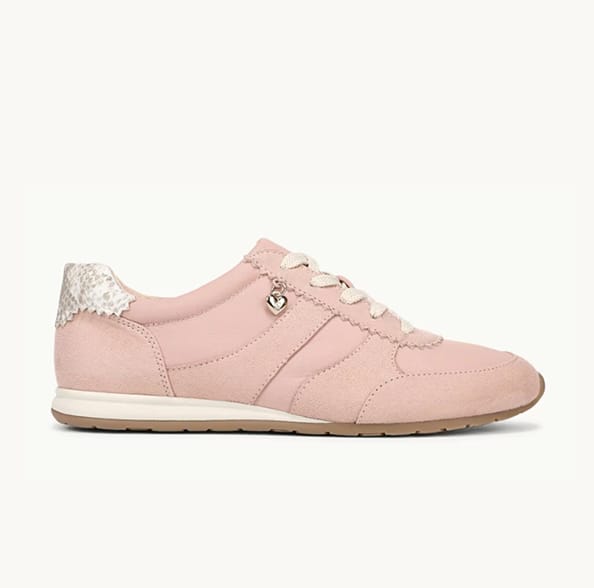 A side view of a light pink sneaker with the toe facing right. 