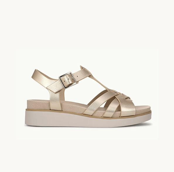 A side view of a gold strappy wedge sandal with the toe facing right. 