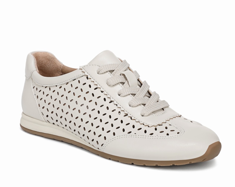 An angled view of a cream colored women's sneaker with perforated details on the side of the shoe. 