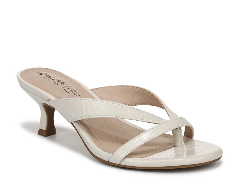 An angled view of a strappy heeled sandal in a cream croco print. 