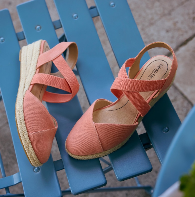 A pink pair of Lifestride heeled wedges on a blue patio chair