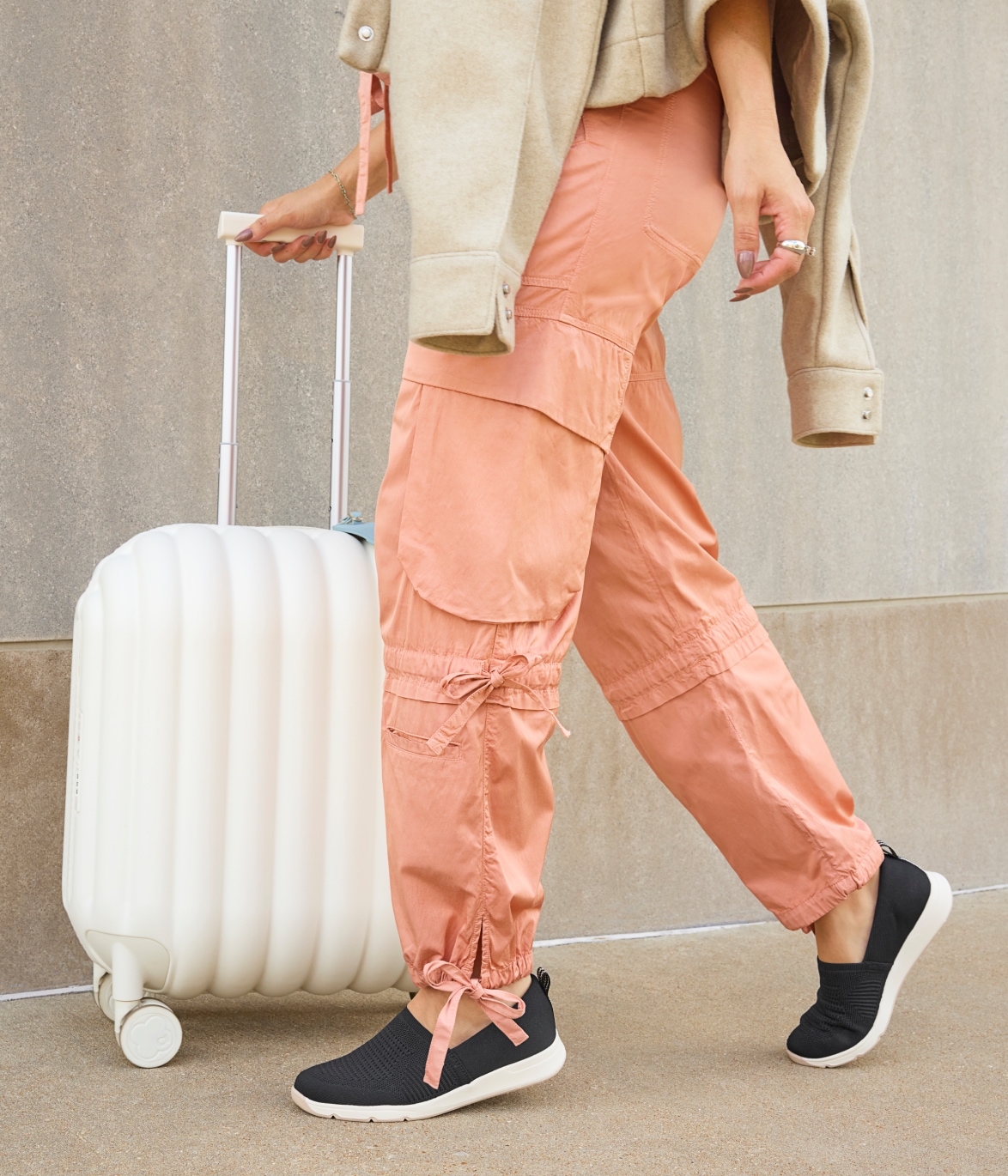 a model wearing LifeStride travel shoes while walking with white luggage