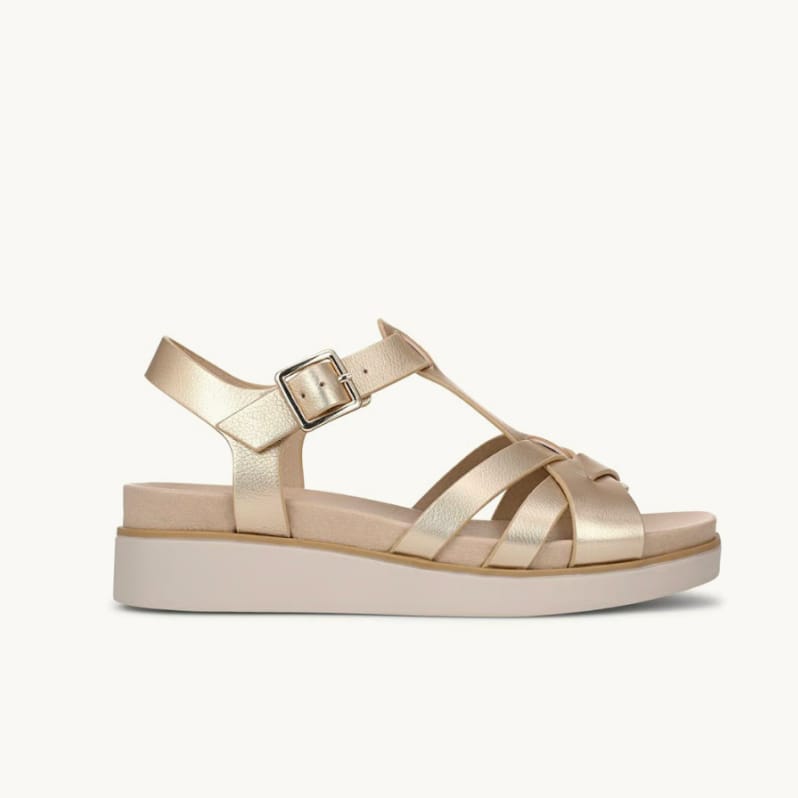 Side view of a women's strappy wedge sandal in gold faux leather.