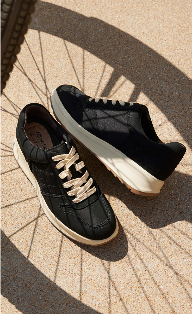 A pair of LifeStride Revival sneaker shoes with the shadow of a bicycle wheel in the background