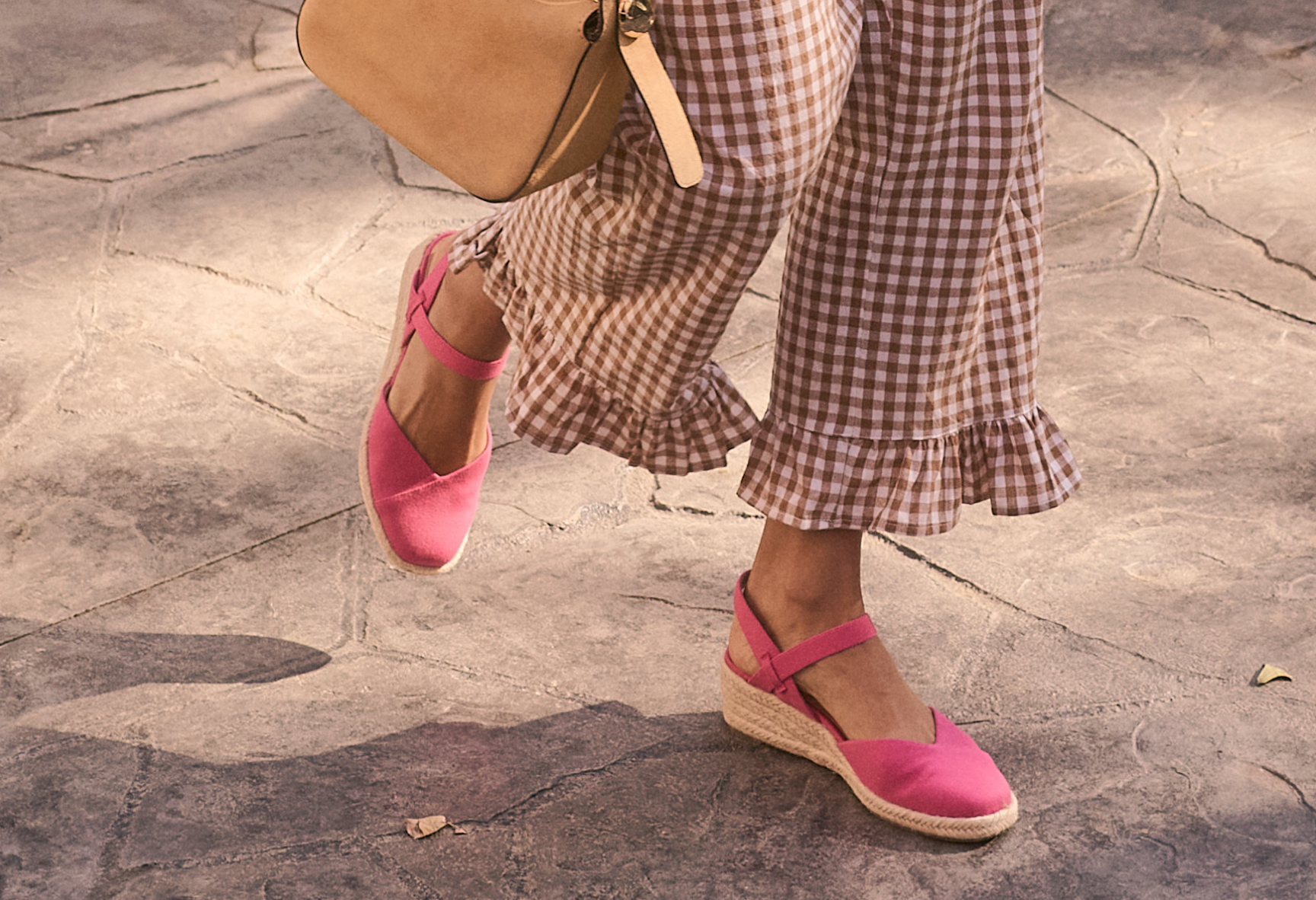 A closeup view of a woman wearing plaid pants and pink espadrilles.