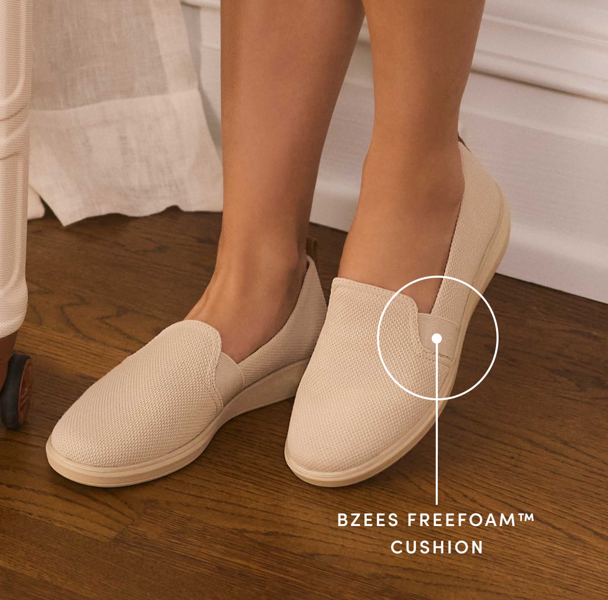 A closeup of a woman wearing a pair of perforated tan slip on shoes with text reading 